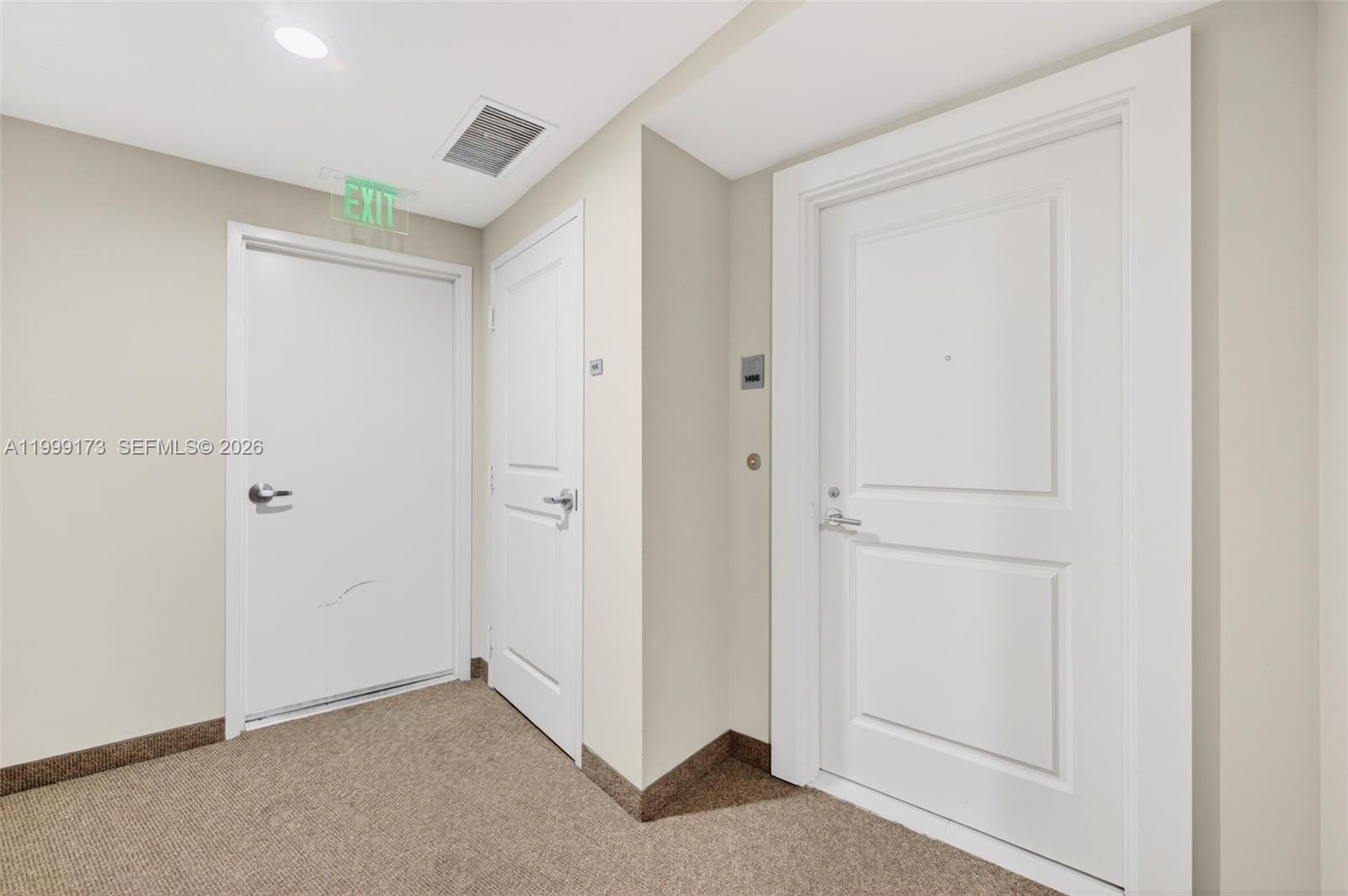 A hallway features three white doors, beige walls, and brown carpeted flooring — 1 N Ocean Blvd # 1408, Pompano Beach FL 33062, POMPANO BEACH, FL