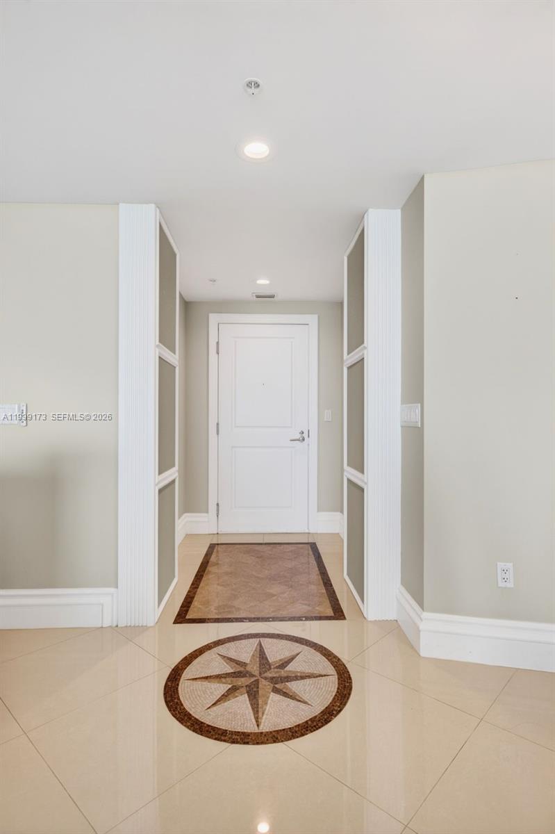 A hallway features a white door, tiled floors with a compass inlay, and decorative wall panels — 1 N Ocean Blvd # 1408, Pompano Beach FL 33062, POMPANO BEACH, FL