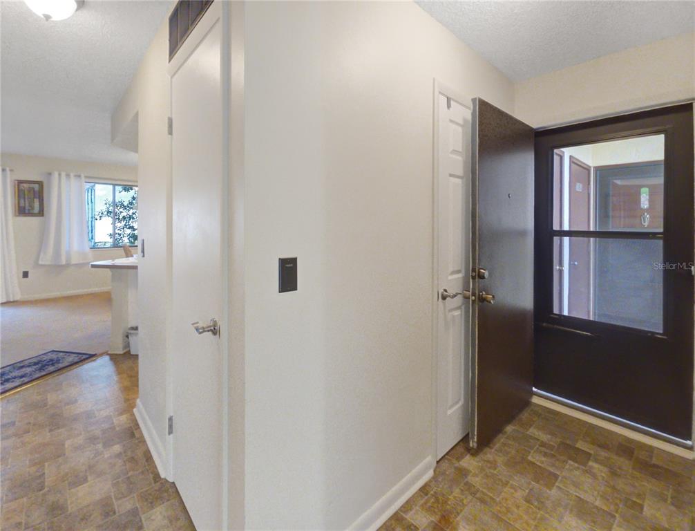 An entryway features a brown front door, tiled flooring, and a view into a living area — 504 SILVER COURSE UNIT A, OCALA, FL