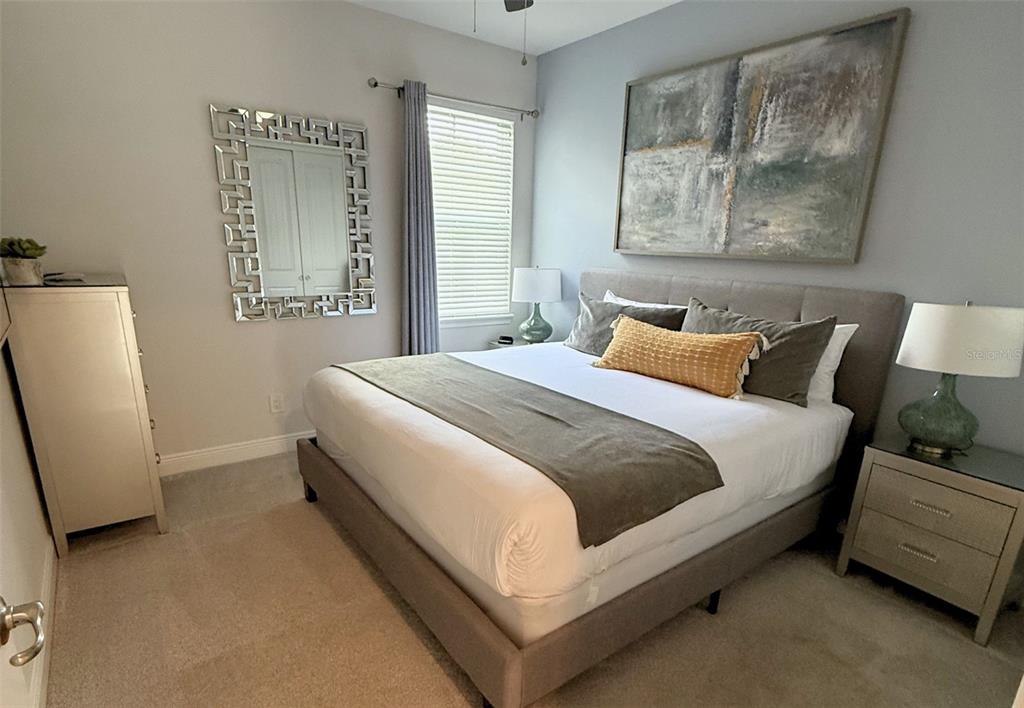 A bedroom features a bed with a gray headboard, a dresser, and a decorative mirror — 448 SOUTHFIELD STREET, KISSIMMEE, FL