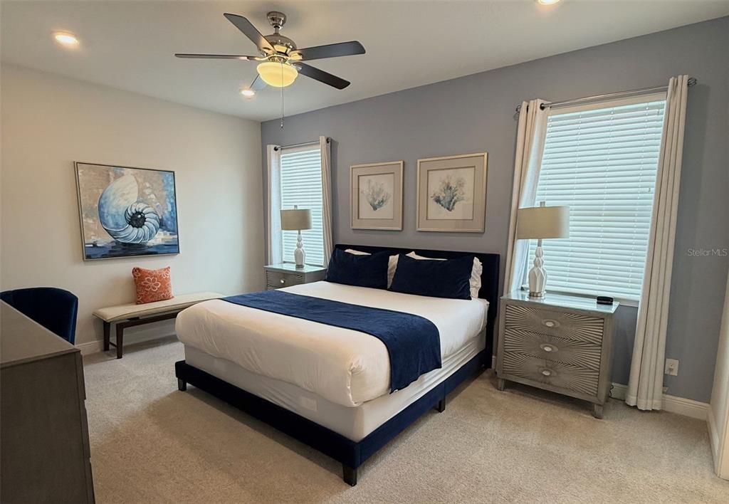 A bedroom features a bed with navy bedding, two windows, and a ceiling fan — 448 SOUTHFIELD STREET, KISSIMMEE, FL