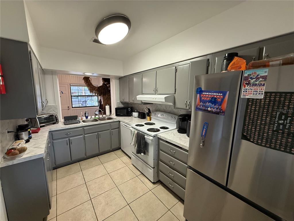 A kitchen with gray cabinets, white countertops, tile flooring, and a view of Chewbacca outside — 1530 NW 6TH AVENUE, GAINESVILLE, FL