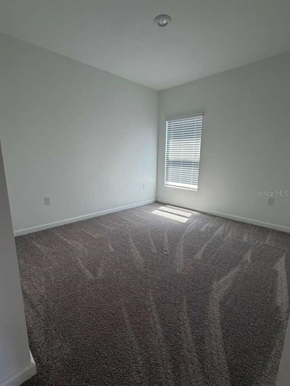 An empty bedroom features gray carpet, white walls, and a single window with blinds — 2350 BURNEY FALLS LANE, DAVENPORT, FL