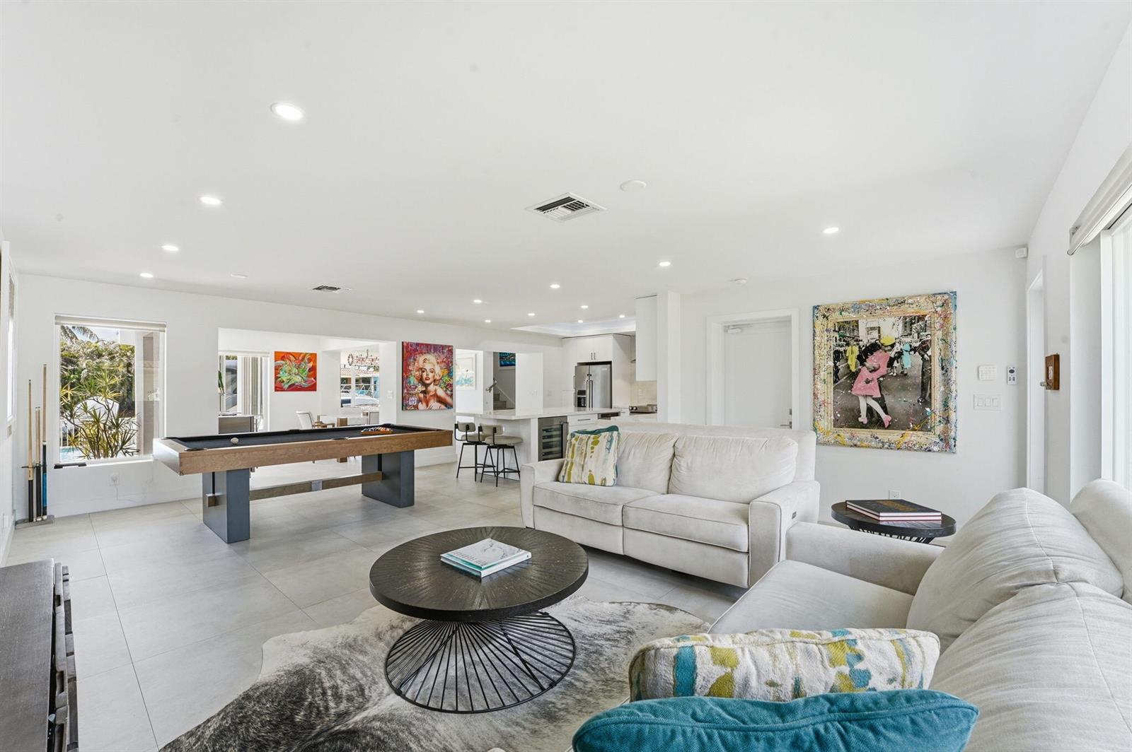 A bright, open-concept living area features a pool table, white sofas, and modern artwork — 120 SE 12th Court, Pompano Beach FL 33060, POMPANO BEACH, FL