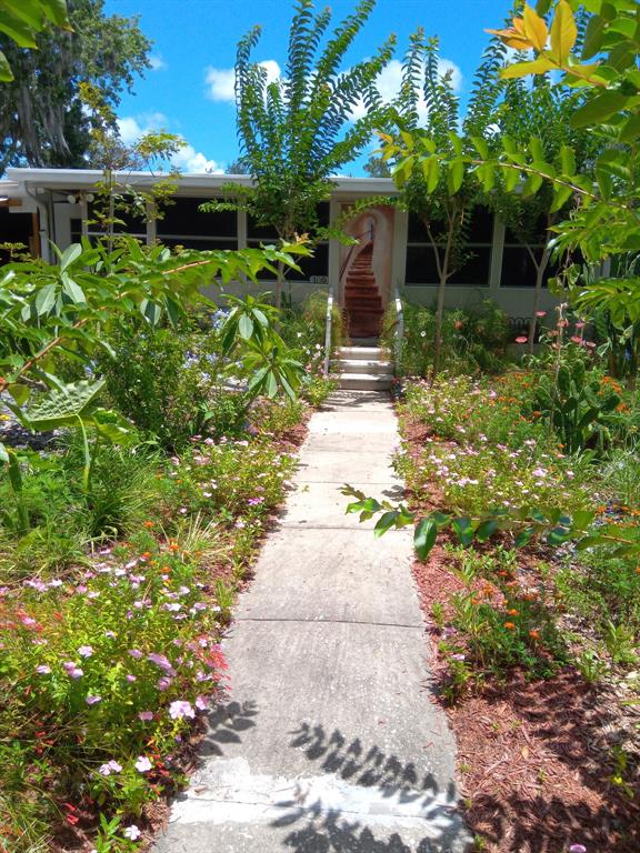 A mobile home exterior features a concrete patio, a metal awning, and white fencing — 109 FERN DRIVE, DEBARY, FL