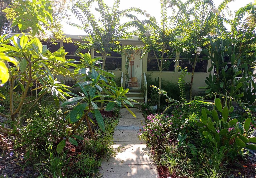 A concrete walkway leads to the front entrance of a house surrounded by lush landscaping — 109 FERN DRIVE, DEBARY, FL