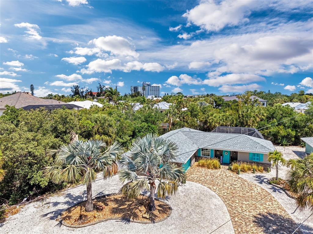 An aerial view shows a single-story house with a brick driveway and two palm trees — 307 AVENIDA DE PARADISIO, SARASOTA, FL