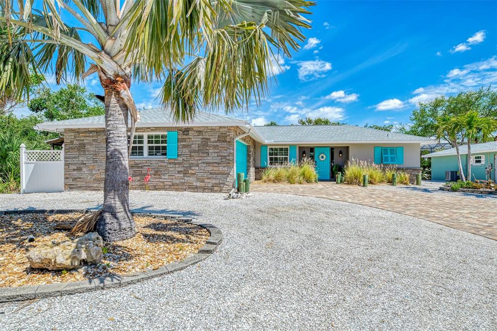 A single-story house with stone siding, turquoise shutters, and a gravel driveway under a palm tree — 307 AVENIDA DE PARADISIO, SARASOTA, FL