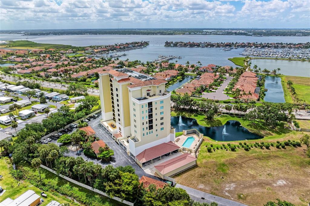 An aerial view shows a tall residential building with a pool and fountains nearby — 501 HABEN BOULEVARD UNIT 505, PALMETTO, FL