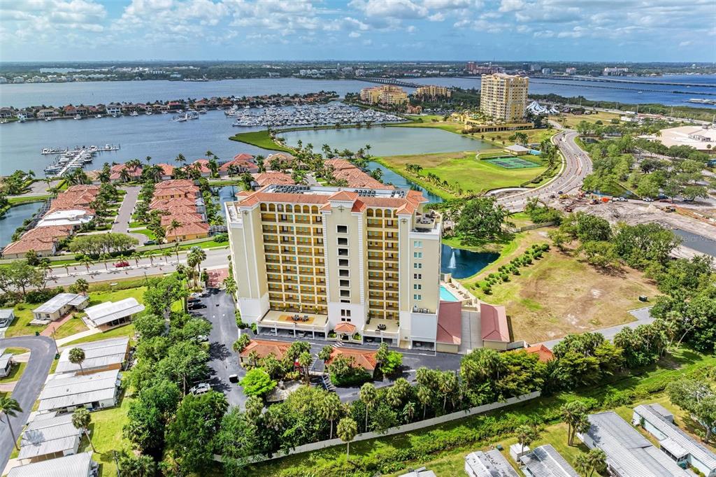 An aerial view shows a tall, multi-story residential building surrounded by water, landscaping, and roads — 501 HABEN BOULEVARD UNIT 505, PALMETTO, FL