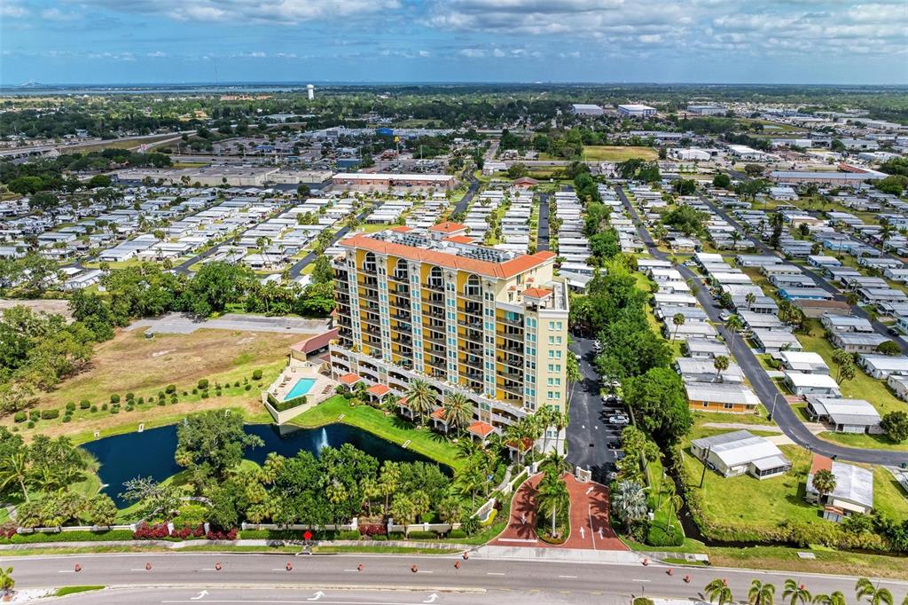 An aerial view shows a tall apartment building next to a pond and mobile homes — 501 HABEN BOULEVARD UNIT 505, PALMETTO, FL