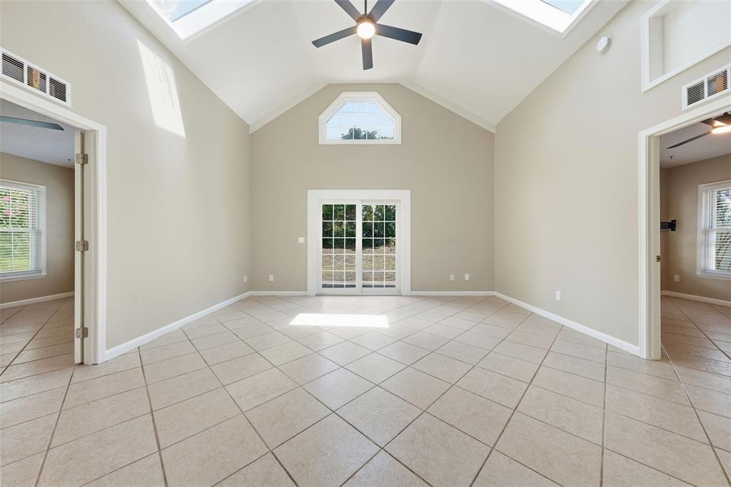 A bright room with vaulted ceilings, a ceiling fan, tile flooring, and sliding glass doors — 917 ALABAMA WOODS LANE, ORLANDO, FL