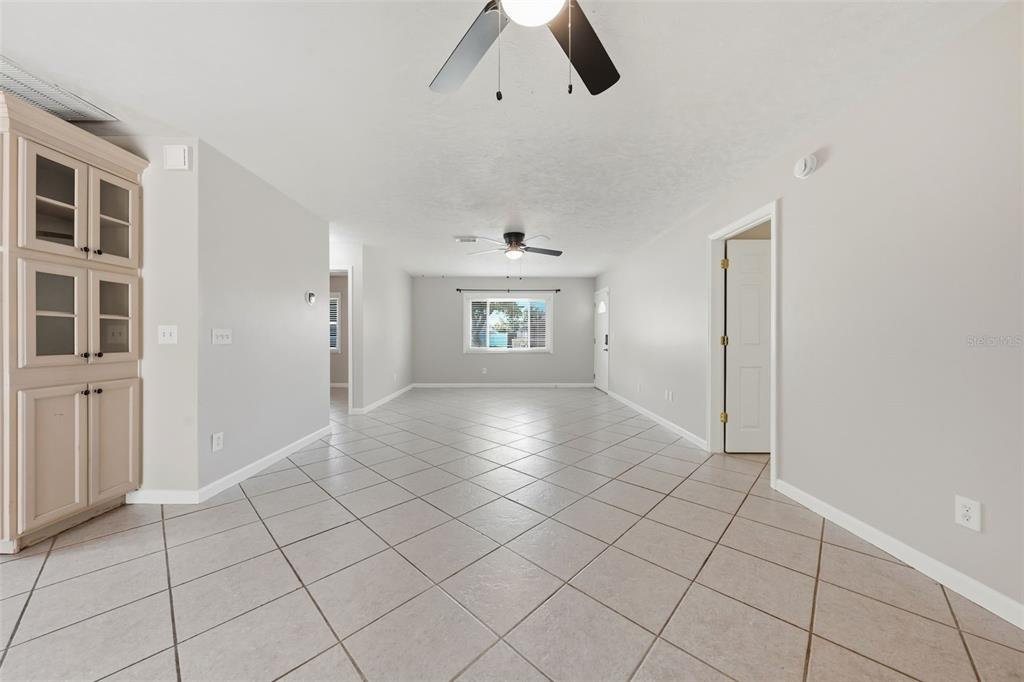 An empty room features light-colored tile flooring, a ceiling fan, and a built-in cabinet — 917 ALABAMA WOODS LANE, ORLANDO, FL