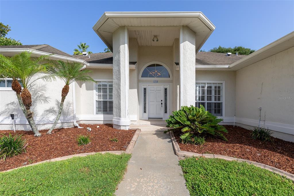 The exterior of a single-story house features a covered entryway with white columns — 1058 ALMOND TREE CIRCLE, ORLANDO, FL