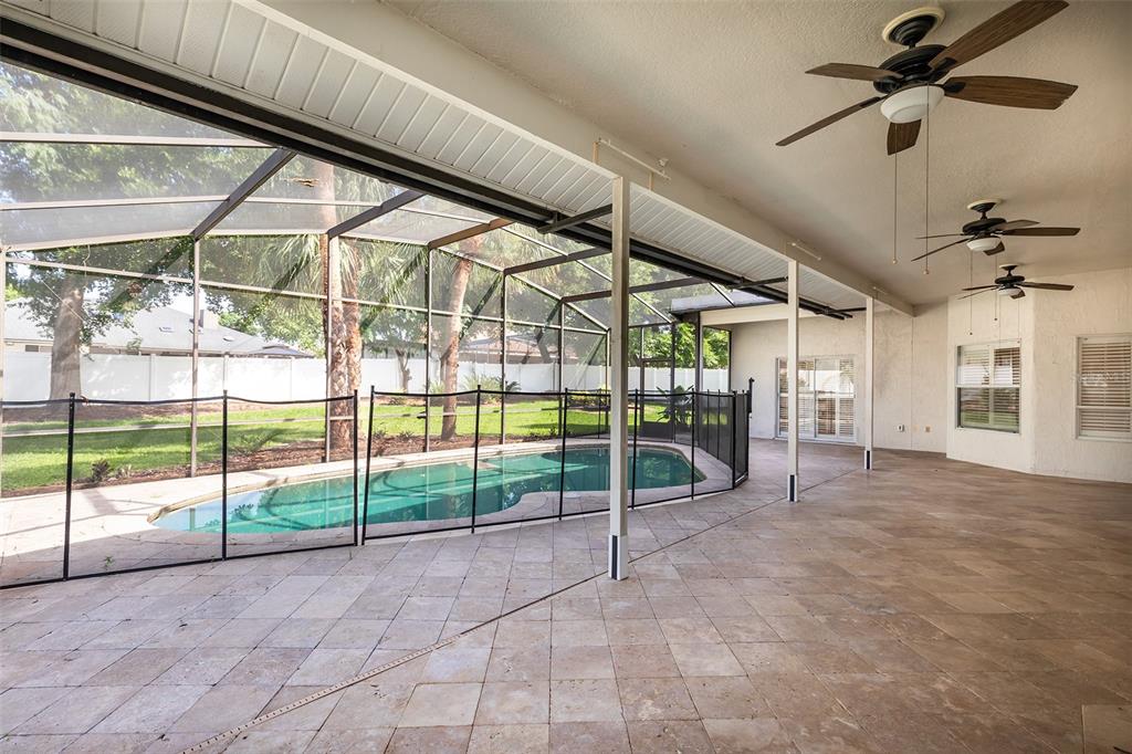 A covered patio with tile flooring overlooks a screened-in swimming pool and backyard — 1058 ALMOND TREE CIRCLE, ORLANDO, FL