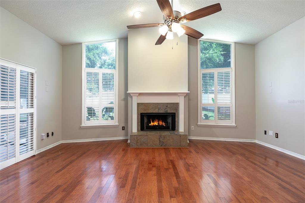 A living room features hardwood floors, a central fireplace, and two tall windows with shutters — 1058 ALMOND TREE CIRCLE, ORLANDO, FL