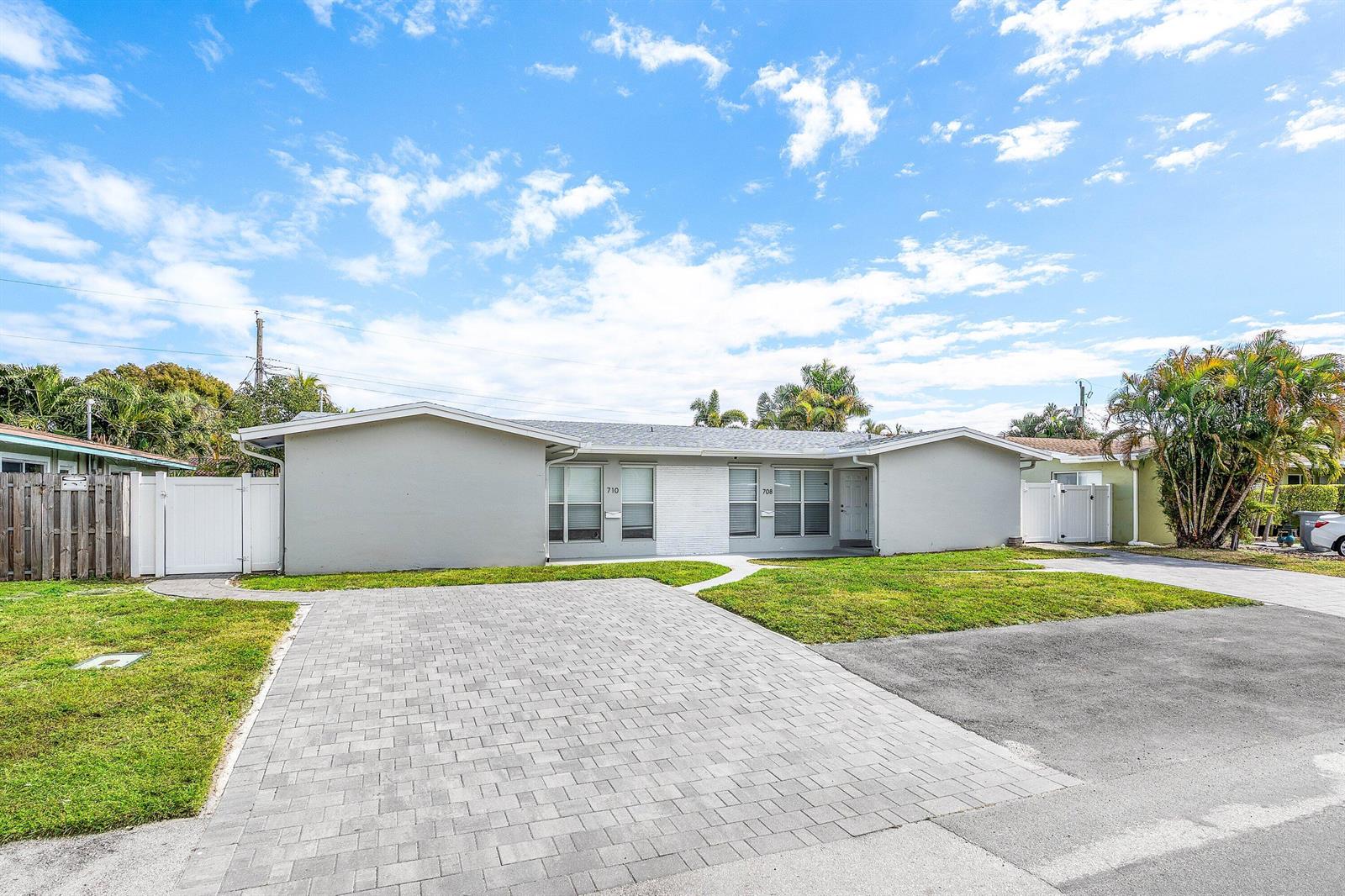 A single-story duplex with a gray exterior, a paved driveway, and a front lawn — 708-710 NE 23rd Avenue, Pompano Beach FL 33062, POMPANO BEACH, FL