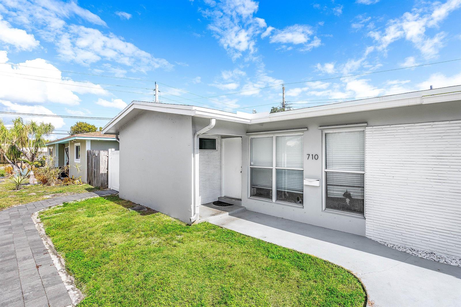 A gray single-story house with a white brick facade, a front walkway, and a lawn — 708-710 NE 23rd Avenue, Pompano Beach FL 33062, POMPANO BEACH, FL