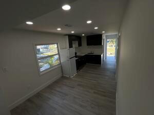 A modern kitchen with dark cabinets and a white refrigerator opens into a living area — 1063 NW 55th Terrace, Miami FL 33127, MIAMI, FL