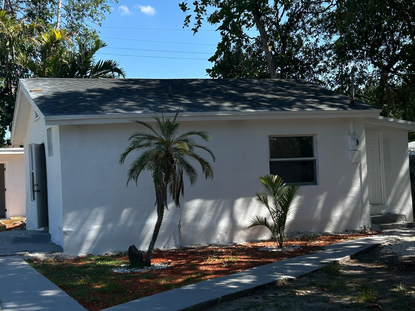 A white, single-story house with a gray shingled roof and two small palm trees — 1063 NW 55th Terrace, Miami FL 33127, MIAMI, FL