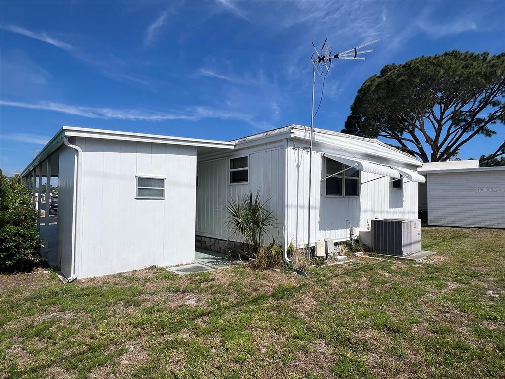 A white mobile home exterior features a metal roof, a tall antenna, and an AC unit — 1500 COUNTY ROAD 1 UNIT 95, DUNEDIN, FL