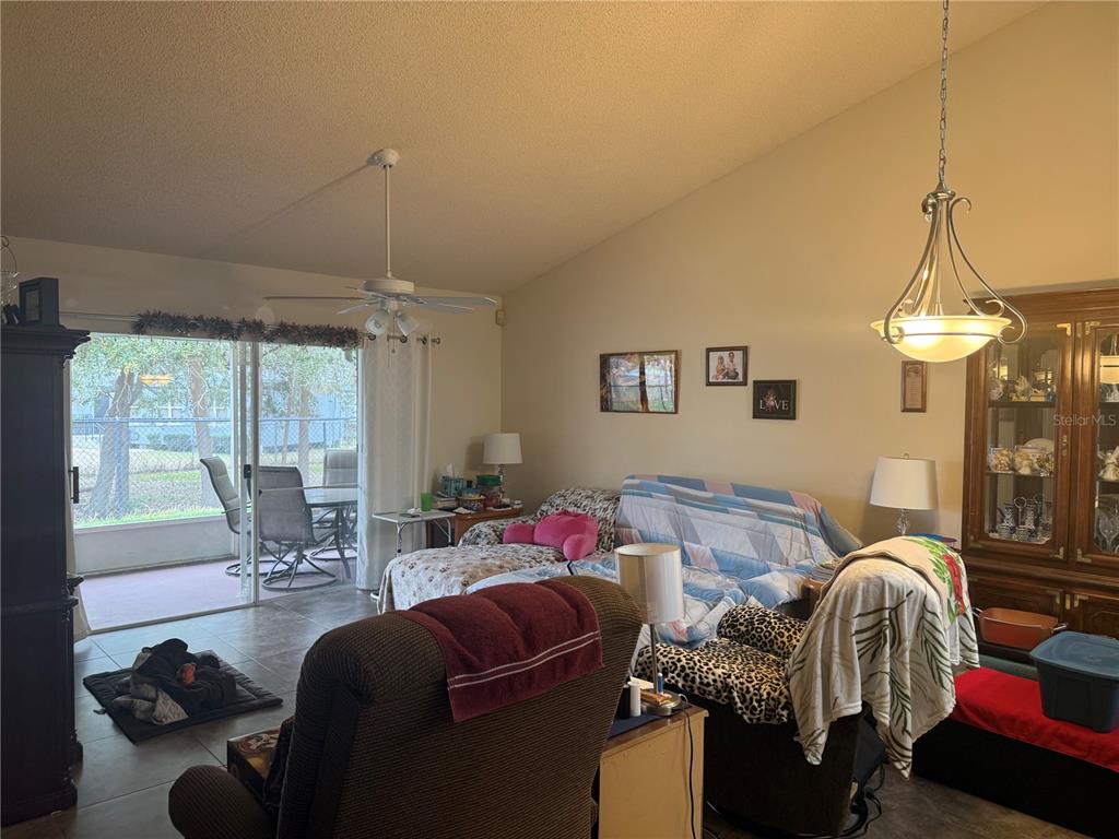 A living room features a vaulted ceiling, tile flooring, a sliding glass door, and furniture — 13143 LAVER LANE, ORLANDO, FL