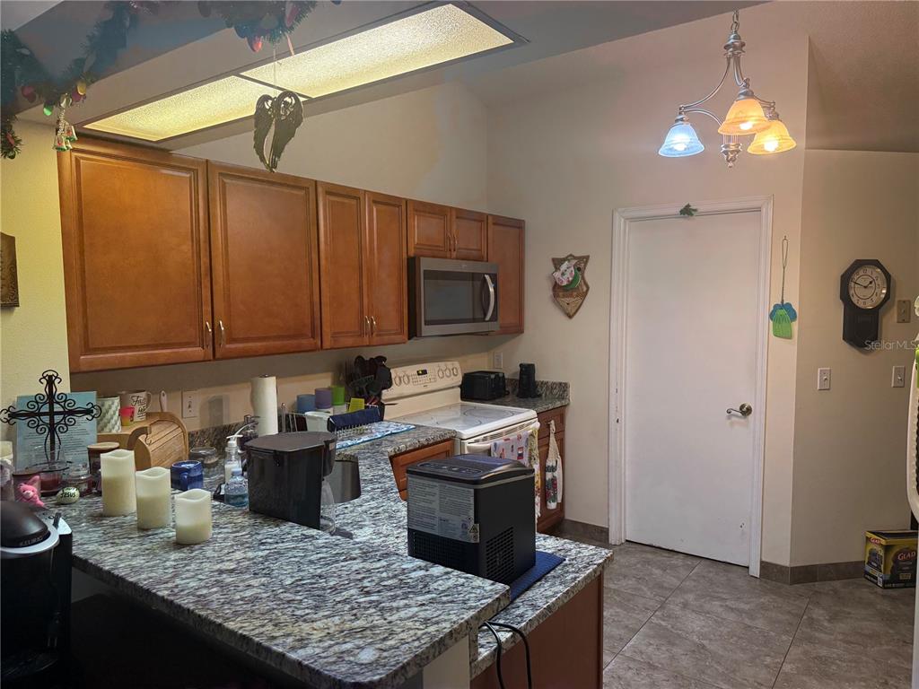 A kitchen features wood cabinets, granite countertops, a microwave, and a white door — 13143 LAVER LANE, ORLANDO, FL