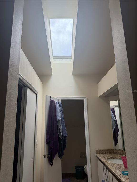 A bathroom features a high ceiling with a skylight, a vanity, and a doorway — 13143 LAVER LANE, ORLANDO, FL