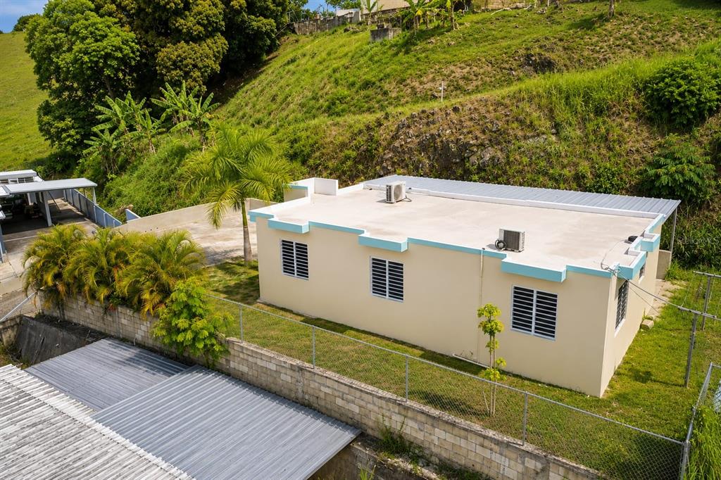 An elevated view shows a light-colored house with a flat roof and metal awnings — Carr 414 SECTOR LOS PUENTES, RINCON, PR