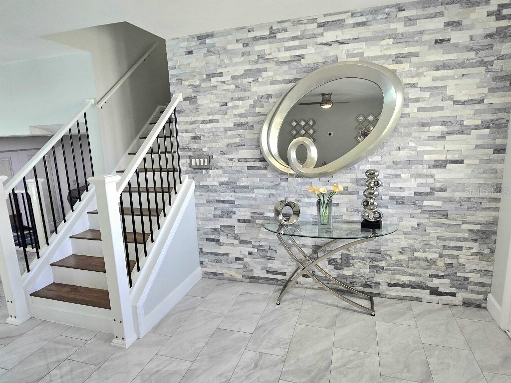 A foyer features a stone accent wall, a glass console table, and a staircase — 7002 DANEWOOD COURT, TAMPA, FL