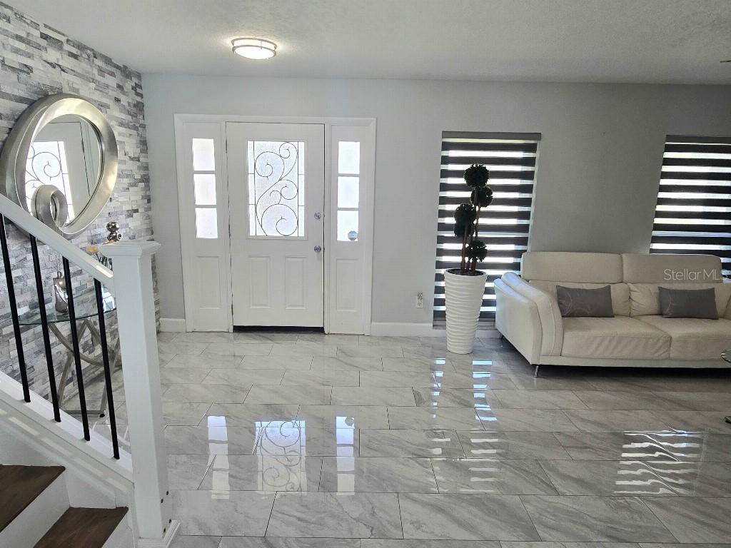 A living room features light gray tile flooring, a white sofa, and a front door — 7002 DANEWOOD COURT, TAMPA, FL