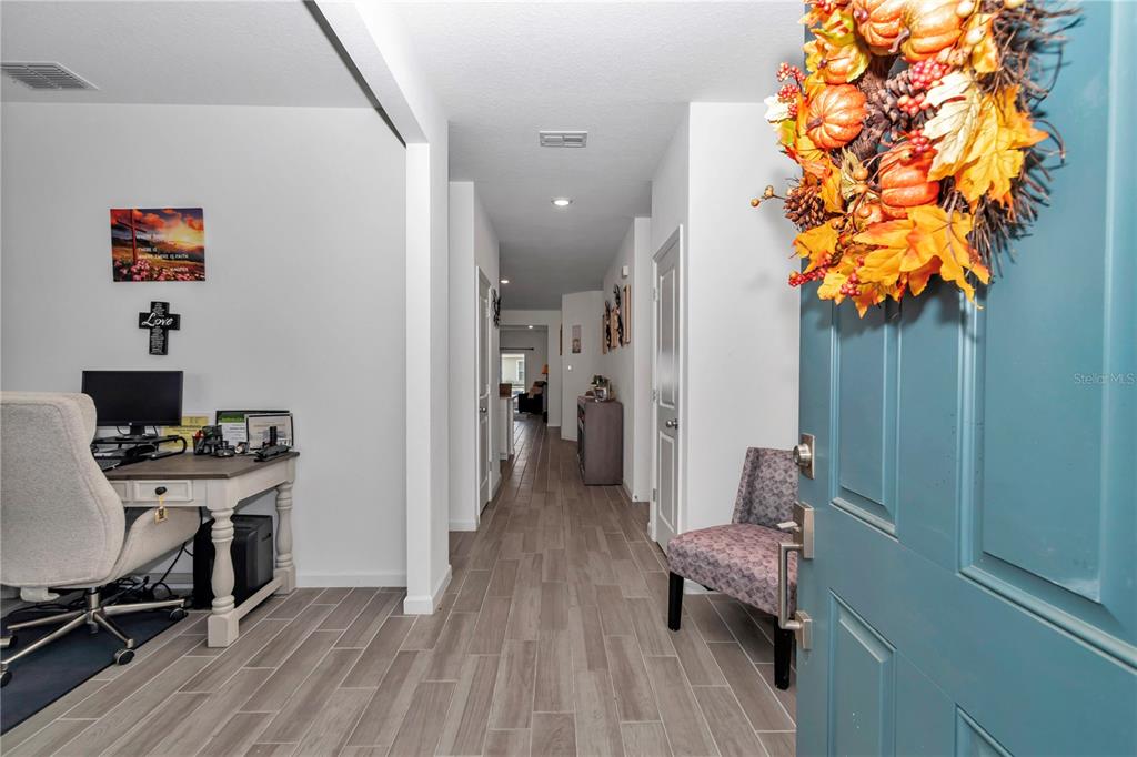 An entryway leads into a hallway with wood-look tile flooring and a home office area — 5660 SW 93RD STREET, OCALA, FL