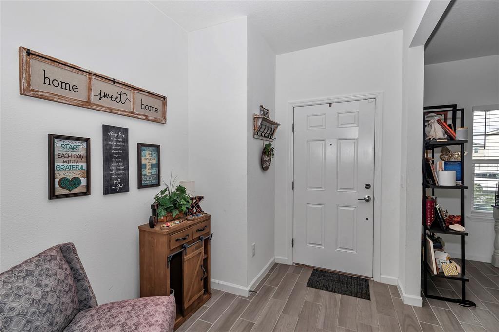An entryway features a white front door, wood-look tile flooring, and a small wooden console table — 5660 SW 93RD STREET, OCALA, FL