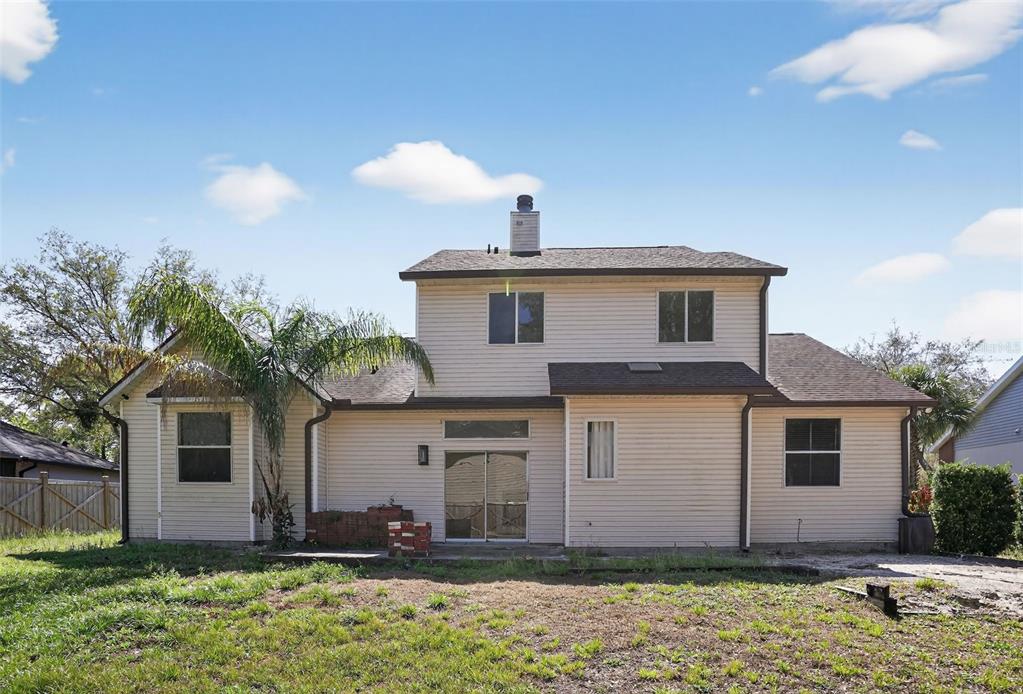 The exterior rear view of a two-story house with light siding and a brick planter — 902 LINGO COURT, OVIEDO, FL
