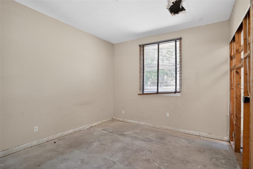 An unfinished room with beige walls, a window with blinds, and exposed wall studs — 902 LINGO COURT, OVIEDO, FL