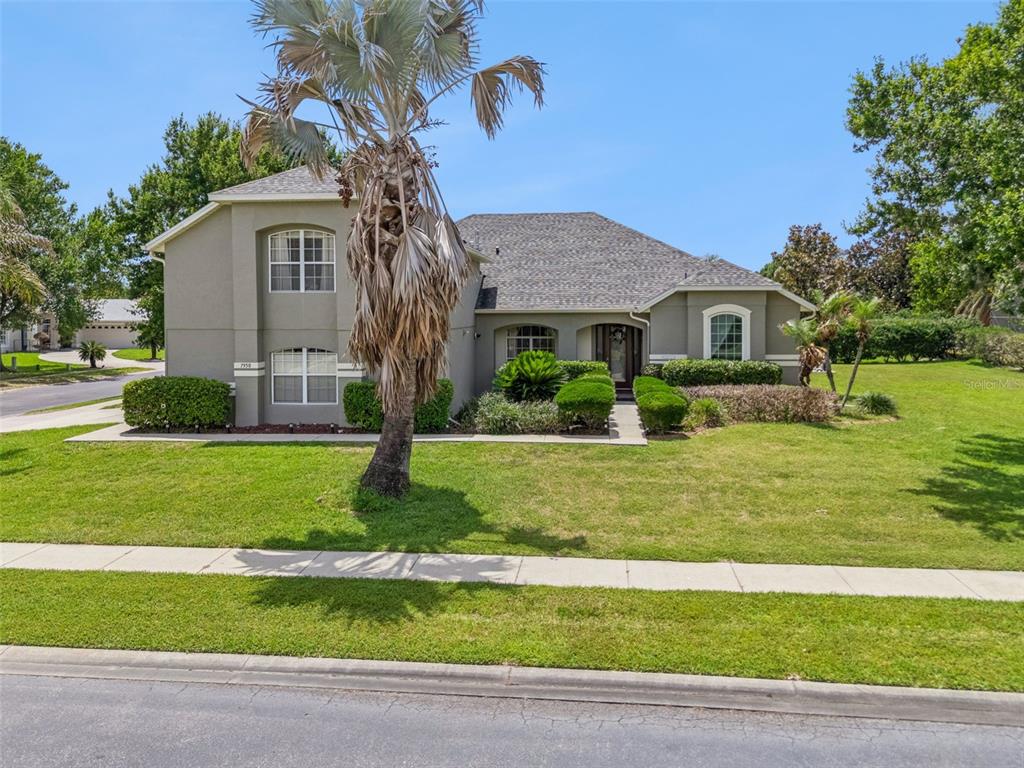 A two-story house with a gray stucco exterior, a shingled roof, and a palm tree — 7950 SEA PEARL CIRCLE, KISSIMMEE, FL