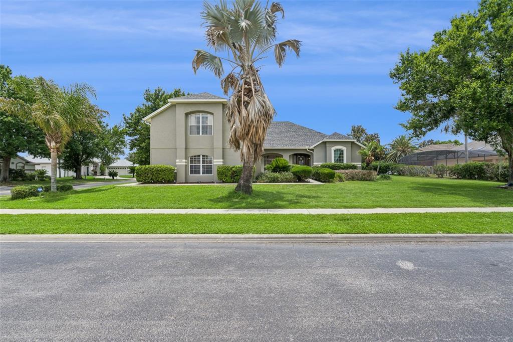 A two-story house with a palm tree in the front yard and a green lawn — 7950 SEA PEARL CIRCLE, KISSIMMEE, FL