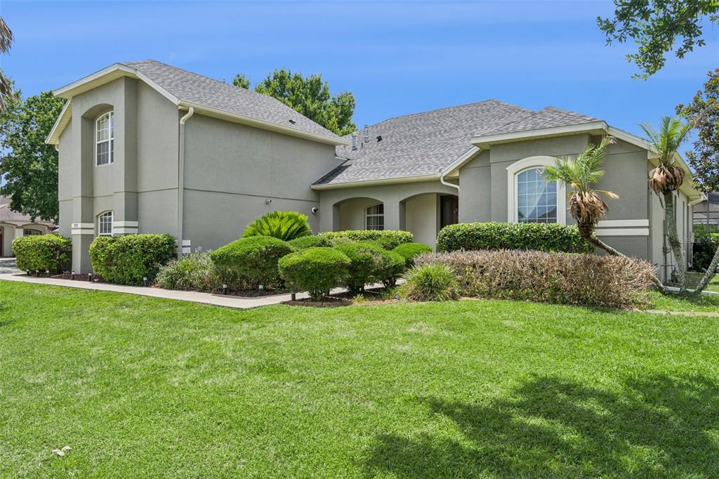 A two-story house with a stucco exterior, a shingled roof, and manicured landscaping — 7950 SEA PEARL CIRCLE, KISSIMMEE, FL