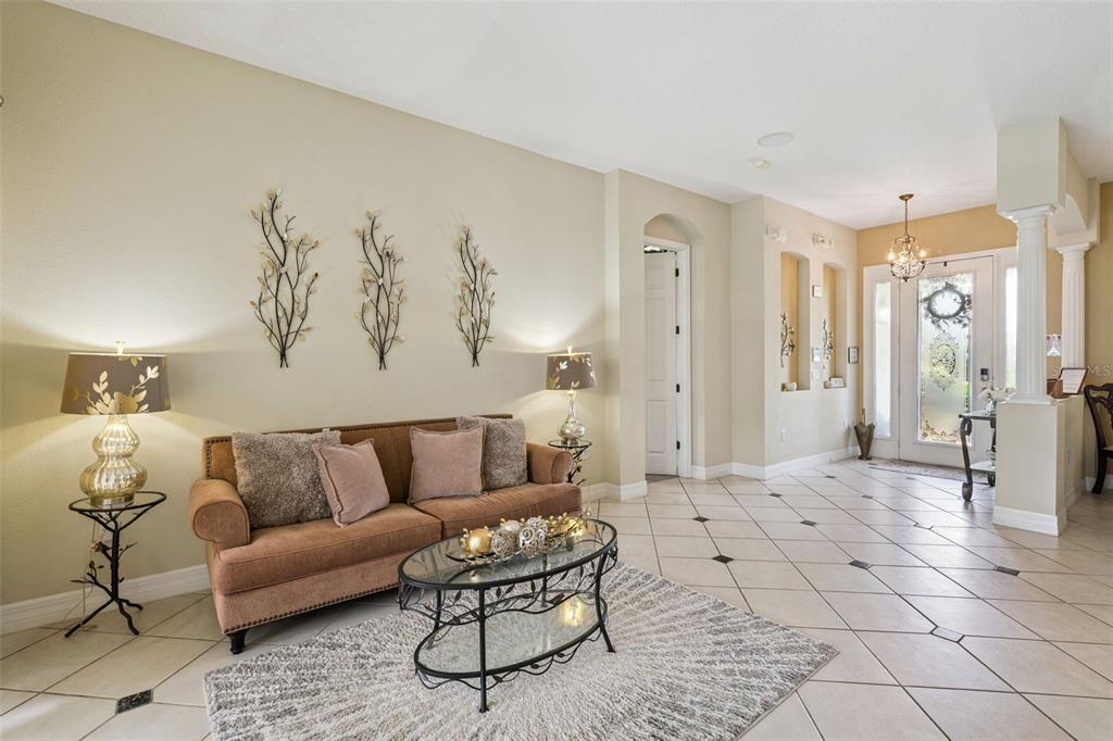 A living room features a brown sofa, glass coffee table, and tiled floors with accents — 7950 SEA PEARL CIRCLE, KISSIMMEE, FL