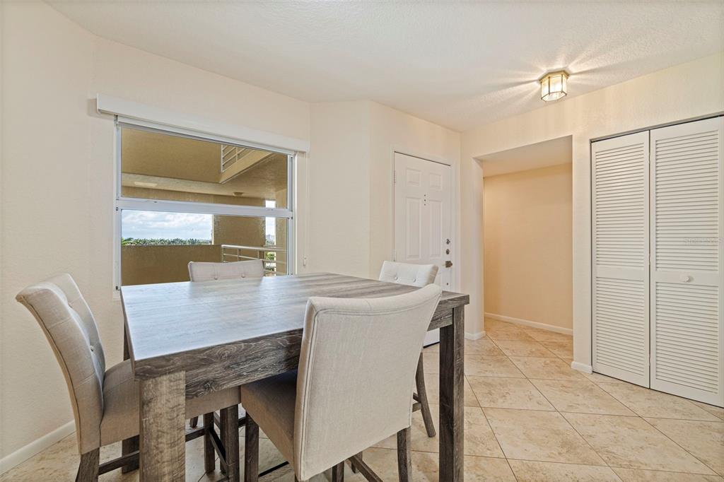 A dining area features a wooden table, four upholstered chairs, tile flooring, and a window — 6105 BAHIA DEL MAR CIRCLE UNIT 683, ST PETERSBURG, FL