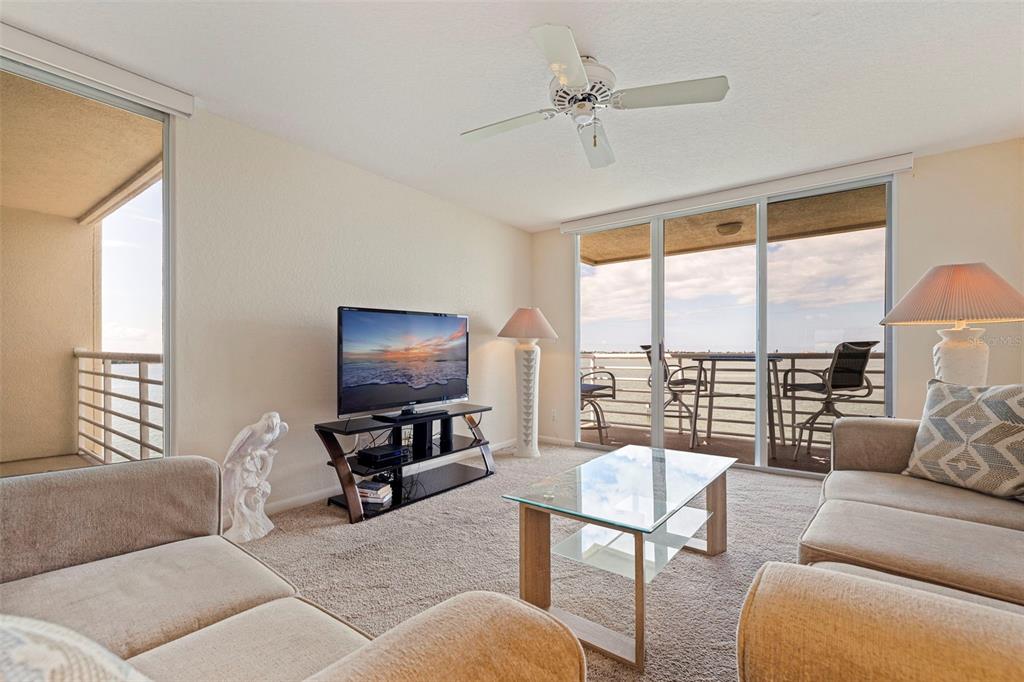 A living room features beige carpet, a glass coffee table, and sliding doors overlooking water — 6105 BAHIA DEL MAR CIRCLE UNIT 683, ST PETERSBURG, FL