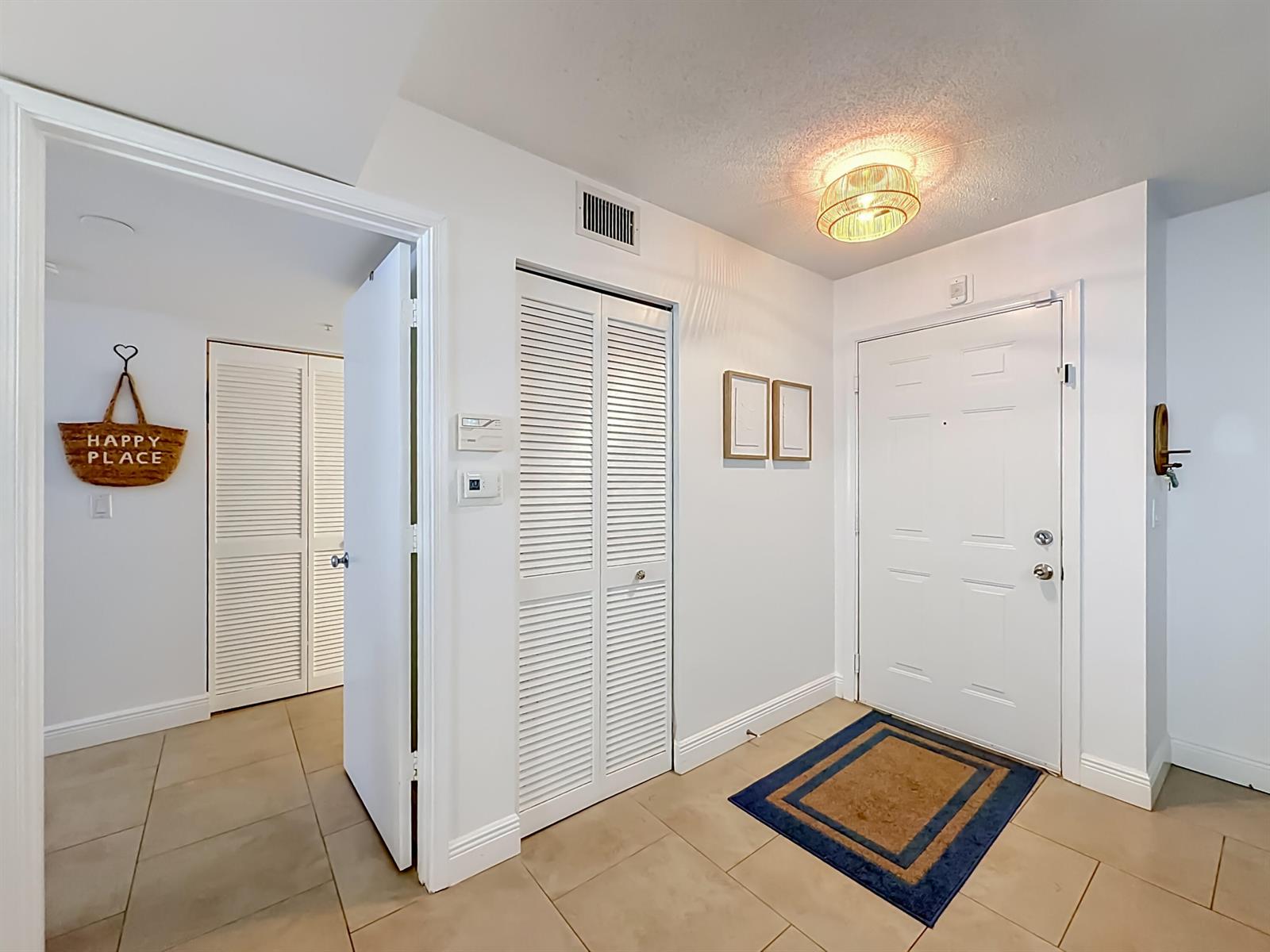 An entryway features a white front door, tiled flooring, louvered closet doors, and a ceiling light — 1341 SE 3rd Avenue # 210, Dania Beach FL 33004, DANIA BEACH, FL