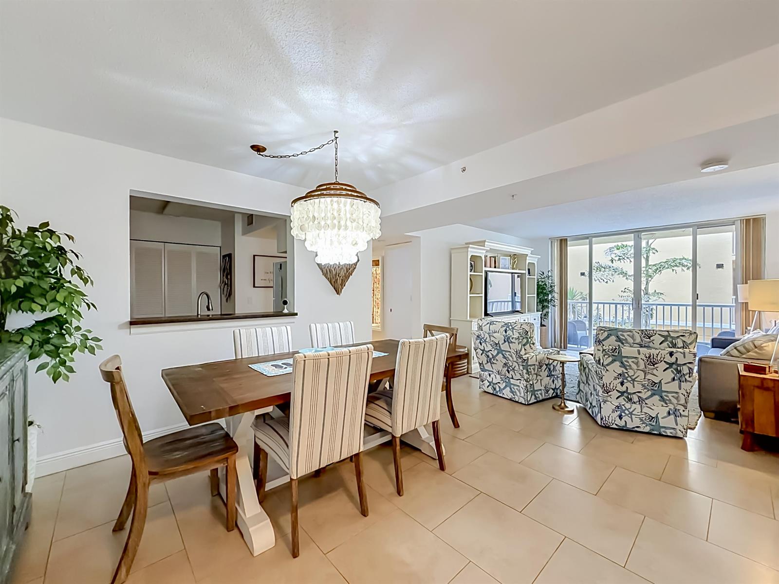 A dining area with a chandelier and a living room with patterned armchairs — 1341 SE 3rd Avenue # 210, Dania Beach FL 33004, DANIA BEACH, FL