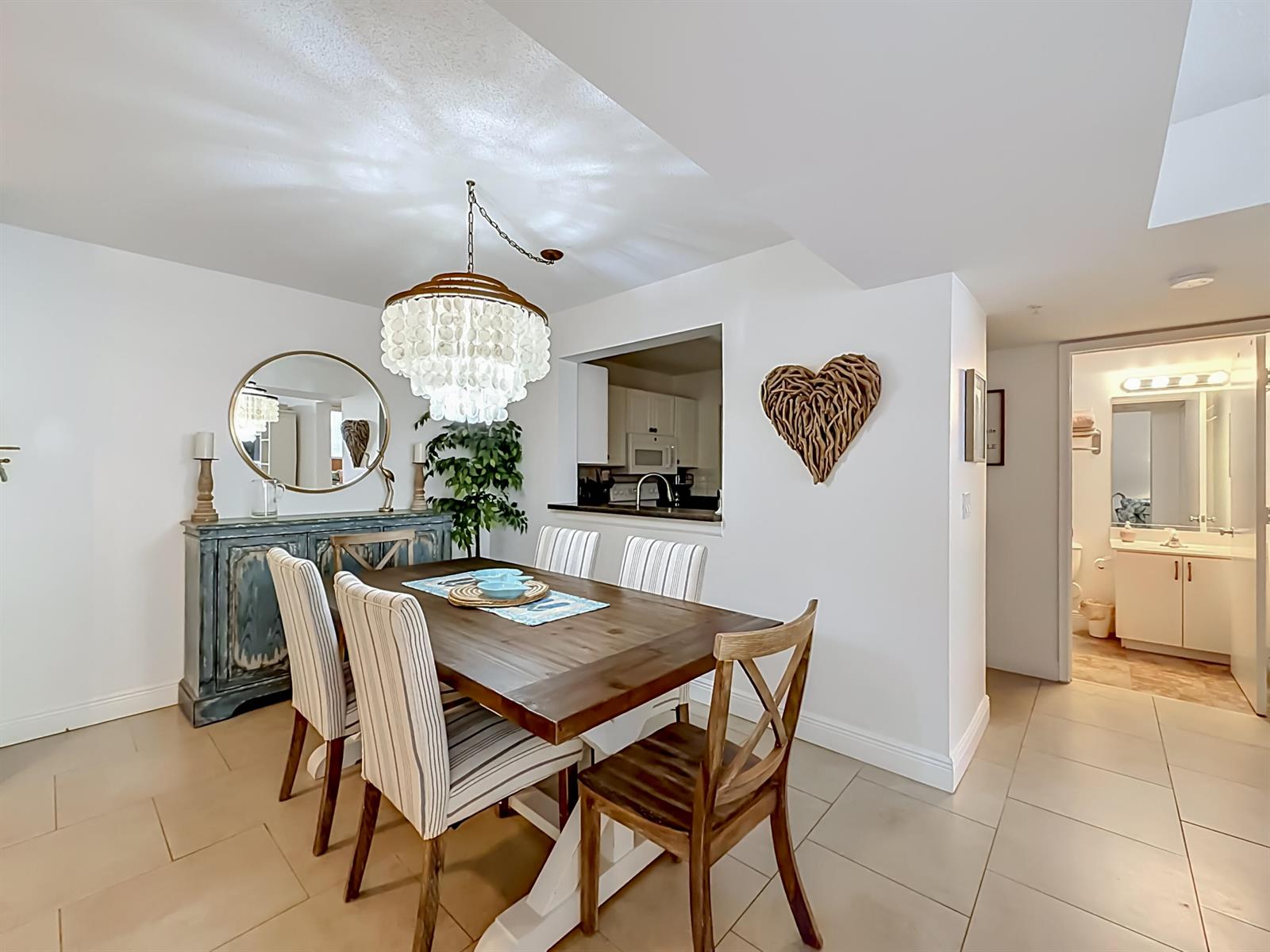 A dining room features a wooden table, striped chairs, a shell chandelier, and a pass-through window — 1341 SE 3rd Avenue # 210, Dania Beach FL 33004, DANIA BEACH, FL