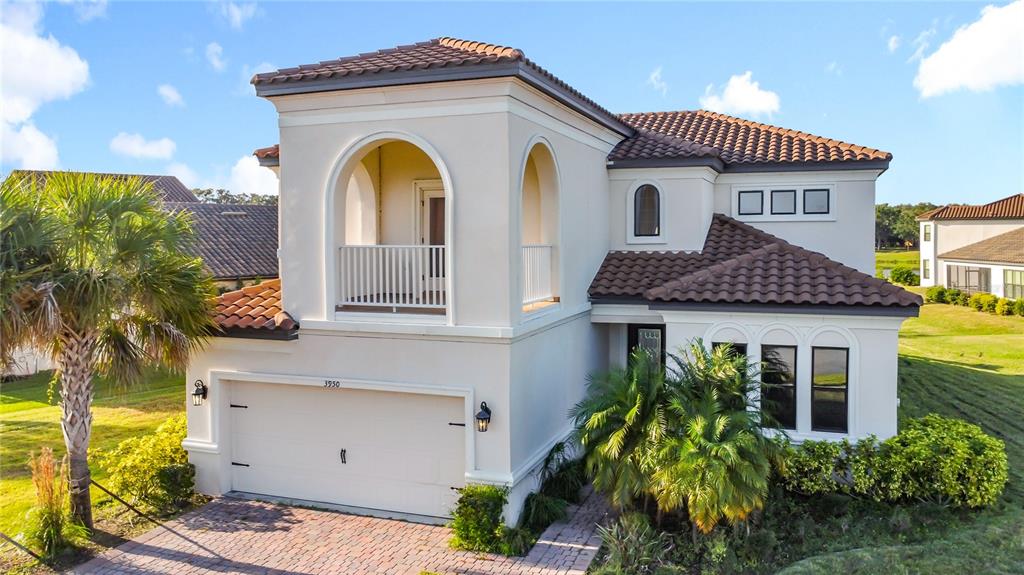 A two-story stucco house features a tile roof, a balcony, and an attached garage — 3950 CARRICK BEND DRIVE, KISSIMMEE, FL