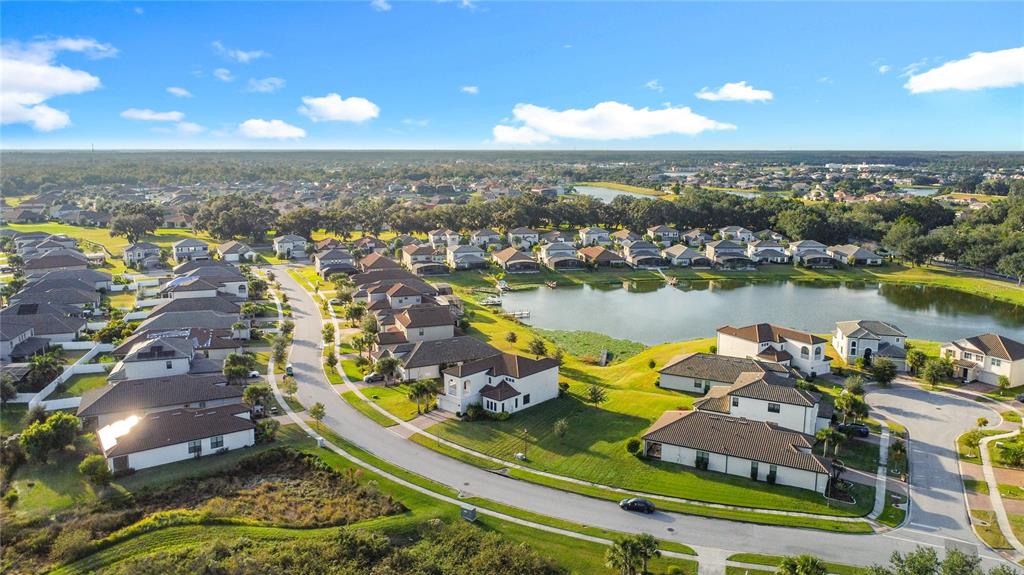 An aerial view shows a suburban neighborhood with houses surrounding a central lake — 3950 CARRICK BEND DRIVE, KISSIMMEE, FL
