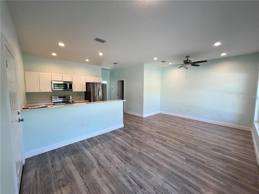 An open-concept kitchen and living area feature light blue walls and wood-look flooring — 1418 N ORANGE STREET, MOUNT DORA, FL