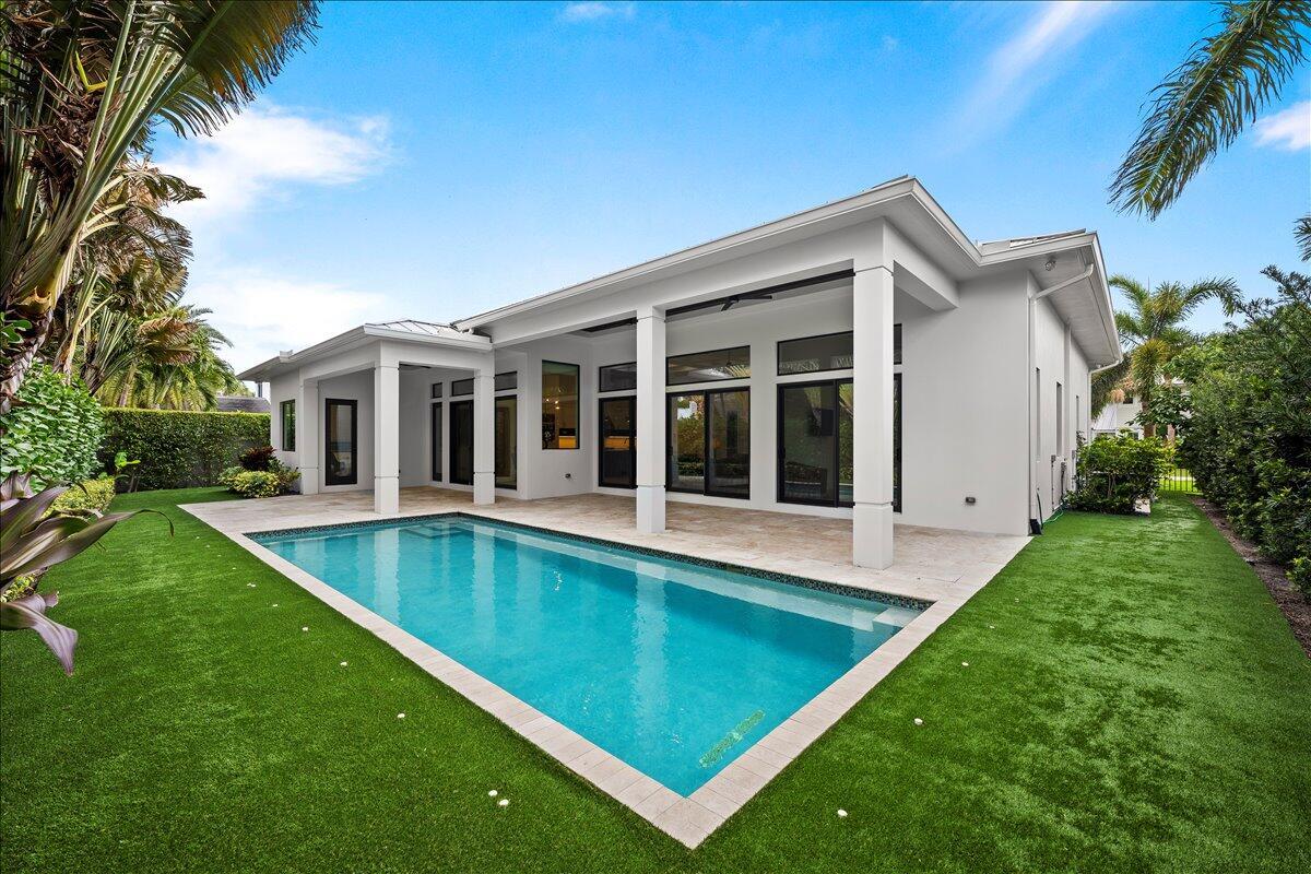 A modern house exterior features a rectangular swimming pool, a covered patio, and green lawn — 187 Shelter Lane, Jupiter FL 33469, JUPITER, FL