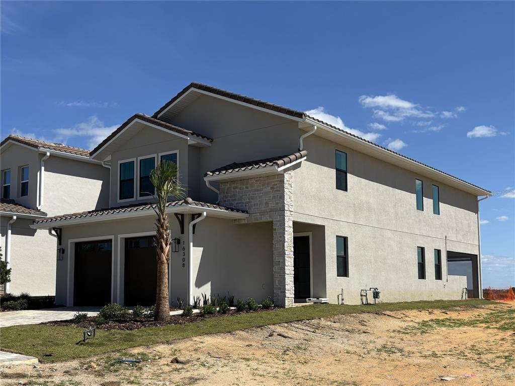 A two-story suburban house with a two-car garage, stone accents, and a paved driveway — 16308 VETTA DRIVE, MONTVERDE, FL