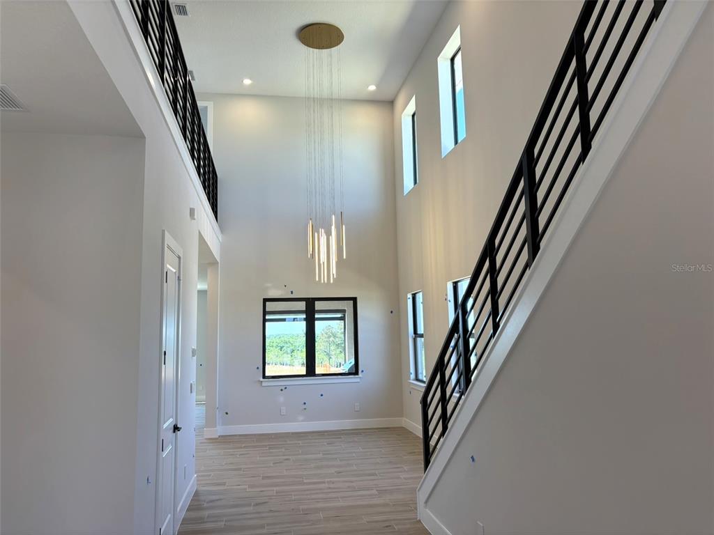 A modern entryway features light wood flooring, a large floor mirror, and a white door — 16308 VETTA DRIVE, MONTVERDE, FL